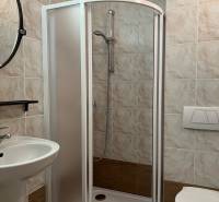 Bathroom with a toilet, shower, and sink in a family house, tiled.