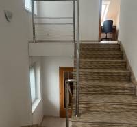A staircase with a railing leads to a room in a family house, white walls.