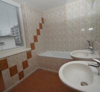 A bathroom with a bathtub, two sinks, a window, and decorative tiles in a family house.
