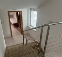 A staircase with carpet and railing leads to a room with a bed in a family house.