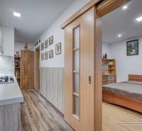 Kitchen corner with a cooktop and a bed, 3-room apartment with a wooden decor floor.