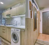 A kitchen in a 3-room apartment with a wood-patterned floor and built-in appliances.