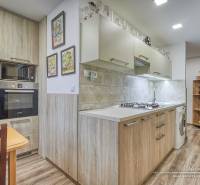 A kitchen in a 3-room apartment with an induction cooktop and a floor with a wood decor.