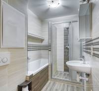 Bathroom in a 3-room apartment with a bathtub, shower corner, and floor with a wooden decor.