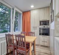 Dining area in a 3-room apartment with wood-patterned flooring, large windows, and a built-in oven.