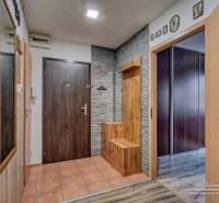 The entrance hall of a three-room apartment with ceramic tiles and a floor with a wooden decor.