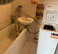 A bathroom in a 3-room apartment with a bathtub, sink, and washing machine in a compact layout.