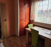 Dining area in a 3-room apartment, wooden decor flooring, green chairs, cabinets.