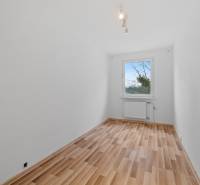 A room in a 4-room apartment with white walls and a wooden decor floor.
