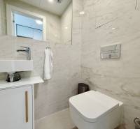 A bathroom in a 3-room apartment with a sink, toilet, and marble tiles.