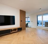 Living room in a 3-room apartment with a wooden decor floor, a television, and a terrace.