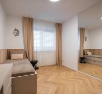 A room in a 3-room apartment with a bed, a mirror, and a floor with a wooden decor.
