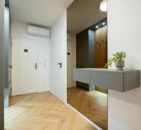 Entrance hallway in a 3-room apartment with a wooden decor floor and a gray cabinet.
