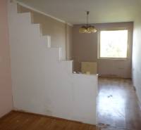 A two-room apartment with a wooden decor floor, staircase, and window offers cozy living.