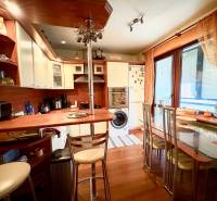 A kitchen in a 3-room apartment with a wooden decor floor and a glass dining table.