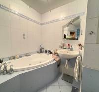 A bathroom with a corner bathtub and a sink in a 3-room apartment.