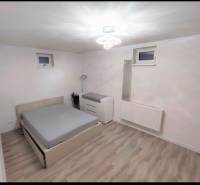 Bedroom in a family house with a bed, dresser, and wooden decor flooring.