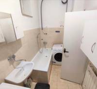 Bathroom with a bathtub, sink, and washing machine in a family house.
