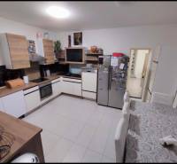A kitchen in a family house with a wooden decor, white appliances, and a dining table.