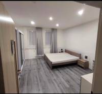 A bedroom in a family house with a wood-patterned floor and large windows.