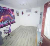 A room with a video game theme and a wooden decor floor in a family house.