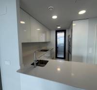 A kitchen in a 3-room apartment with glossy white cabinets and a large work space.