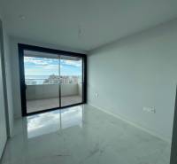 An empty room with a white ceramic floor and a large window in a 3-room apartment.