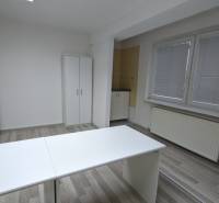 An office with a white desk, a cabinet, and a wooden decor floor.