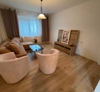 Living room with a corner sofa, glass table, and floor with wood decor.
