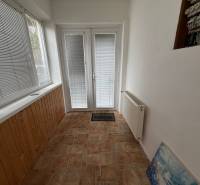 Family house with a glass corridor, tiles, and a radiator, entrance door with blinds.