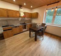 A kitchen in a family house with wooden cabinets and a wooden decor floor.