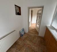 The hallway of a family house with a radiator and light-colored walls, tiled floor.