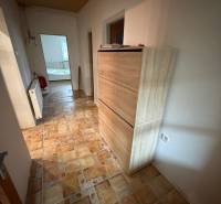 A hallway in a family house with a tiled floor and a wooden ceiling.