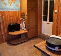 A room in a family house with wooden walls, a map on the wall, and kitchen appliances.