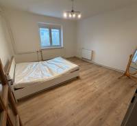 Bedroom of a family house with a double bed and a wooden decor floor.