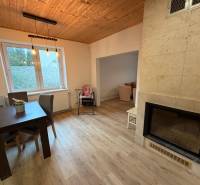 Dining room in a family house with a window, fireplace, and floor with wood decor.