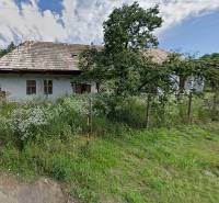 A family house in Nenince with a meadow environment, an older roof, and a garden.