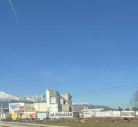 Commercial spaces in Poprad with a backdrop of snow-covered mountains and a clear sky.