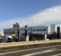 Commercial premises in Poprad with building materials and cars in the background of the highway.
