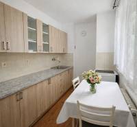A kitchen in a studio apartment with a kitchen unit and a wooden decor floor.