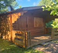 A wooden cottage surrounded by greenery in Úľany nad Žitavou, exudes a cozy and natural atmosphere.