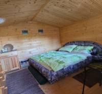 Interior of a wooden cabin with a double bed, a wardrobe, and wall decorations.