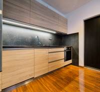A kitchen in a 2-room apartment with wooden cabinets and a floor with a wood pattern.
