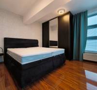 Bedroom in a 2-room apartment with a bed, wardrobe, and floor with a wooden decor.