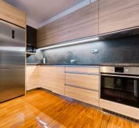 A kitchen in a 2-room apartment with a refrigerator, an oven, and a wooden decor floor.