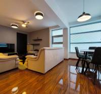 Living room with wood-patterned flooring, sofas, television, and dining table in a two-room apartment.