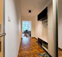 A hallway with tiles and wooden decor leads to the kitchen in a 2-room apartment.