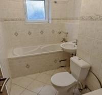 A bathroom in a 2-room apartment with a bathtub, toilet, and sink in light shades.