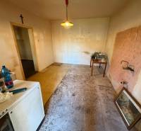 Interior of a family house with an empty room, a table, older furniture, and a dismantled floor.