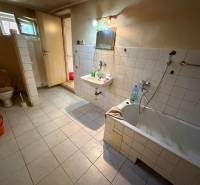A bathroom in a family house with a bathtub, toilet, and sink on a tiled floor.